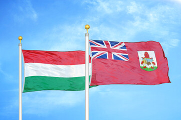 Hungary and Bermuda two flags on flagpoles and blue cloudy sky