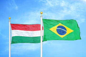 Hungary and Brazil  two flags on flagpoles and blue cloudy sky