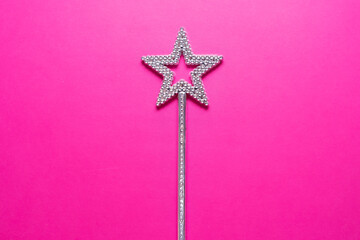 Sparkling magic wand on a pink background. Concept of celebration and magic, copy space.