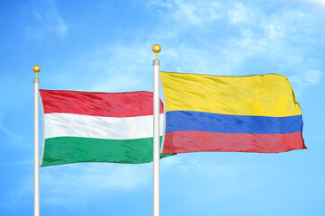 Hungary and Colombia two flags on flagpoles and blue cloudy sky