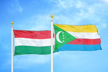 Hungary and Comoros two flags on flagpoles and blue cloudy sky
