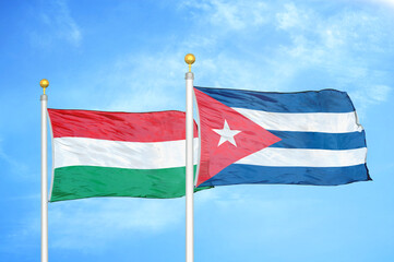 Hungary and Cuba two flags on flagpoles and blue cloudy sky