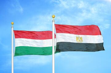 Hungary and Egypt two flags on flagpoles and blue cloudy sky
