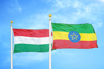 Hungary and Ethiopia two flags on flagpoles and blue cloudy sky