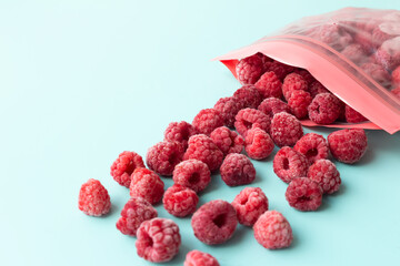 Frozen raspberries in a plastic bag with a fastener on a blue background. Preparations for the...