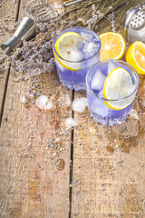 Lavender alcoholic cocktail, Lavandula lemonade with lemon and honey, on wooden background with lavender bunch and barmen utencils, copy space