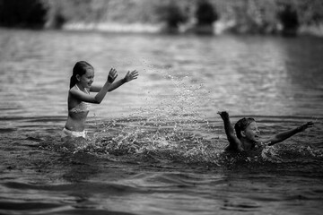 Two naughty little girls bathe in the lake. Black and white photo.