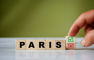 The hand turns the wooden cube and changes the word PARIS with red tick check box and red reject X check box.