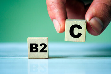 Symbol of B2Cwith word on wooden cube blocks. Hand hold one cube. Business to consumer topic.