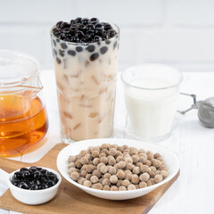 Fototapeta na wymiar Bubble milk tea with tapioca pearl topping ingredient, famous Taiwanese drink on white wooden table background in drinking glass, close up, copy space