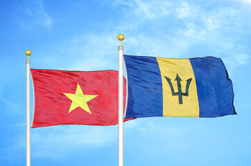 Vietnam and Barbados  two flags on flagpoles and blue sky