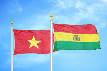 Vietnam and Bolivia  two flags on flagpoles and blue sky