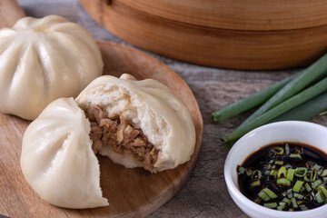 Delicious baozi, Chinese steamed meat bun is ready to eat on serving plate and steamer, close up, copy space product design concept.