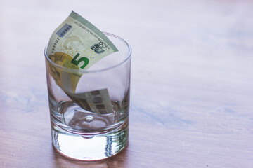 International currency Euro in a glass on a neutral background, space for the inscription. Money