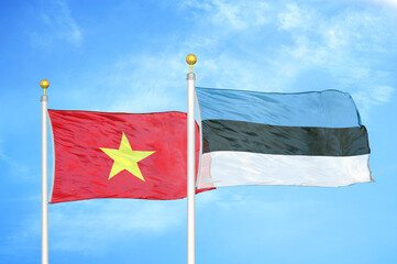 Vietnam and Estonia two flags on flagpoles and blue sky