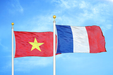 Vietnam and France two flags on flagpoles and blue sky