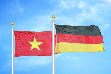 Vietnam and Germany two flags on flagpoles and blue sky