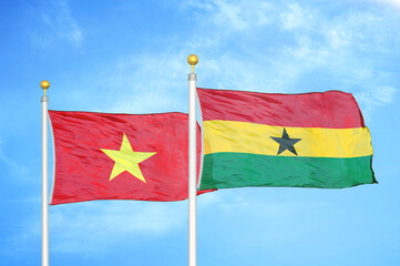 Vietnam and Ghana two flags on flagpoles and blue sky
