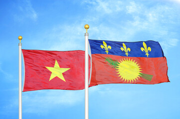 Vietnam and Guadeloupe two flags on flagpoles and blue sky
