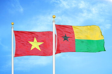 Vietnam and Guinea-Bissau two flags on flagpoles and blue sky