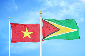 Vietnam and Guyana two flags on flagpoles and blue sky