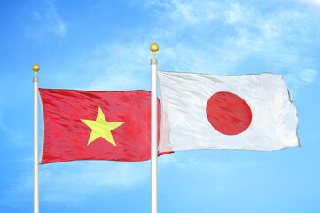 Fototapeta na wymiar Vietnam and Japan two flags on flagpoles and blue sky