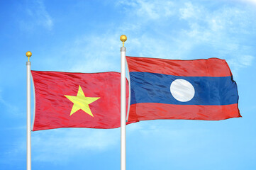 Vietnam and Laos. two flags on flagpoles and blue sky