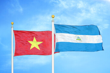 Vietnam and Nicaragua two flags on flagpoles and blue sky