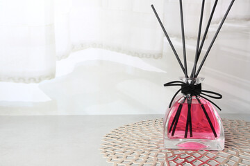 luxury glass aroma reed diffuser bottle with colorful blue , green and pink colour oil are displayed on the grey table in the white bed room