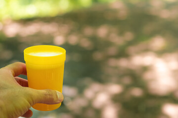 Plastic glass with a drink in hand in nature
