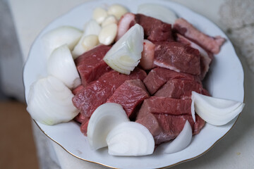 Sliced ​​pieces of meat are on a plate for further cooking