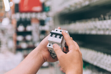 The man holds in his hands toggle switches for electrical wiring. Concept man chooses a product in...