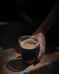 Woman holding iced coffee.
