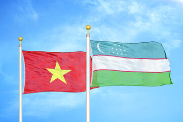 Vietnam and Uzbekistan two flags on flagpoles and blue sky