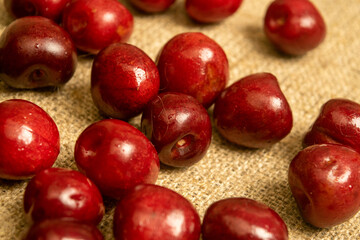 Ripe juicy cherries scattered on a homespun fabric with a rough texture. Close up.
