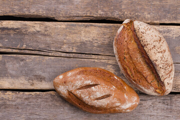 Homemade bread on old wooden background. Two loaves of freshly baked bread on rustic boards. Bakery concept.