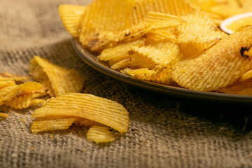 Fluted potato chips on a background of homespun fabric with a rough texture. Close up.