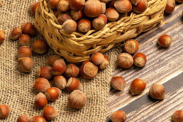 Hazelnuts in a wicker basket and hazelnuts scattered on a background of homespun fabric with a rough texture. Close up.