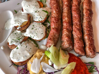 grilled meatballs and potatoes with salad on plate