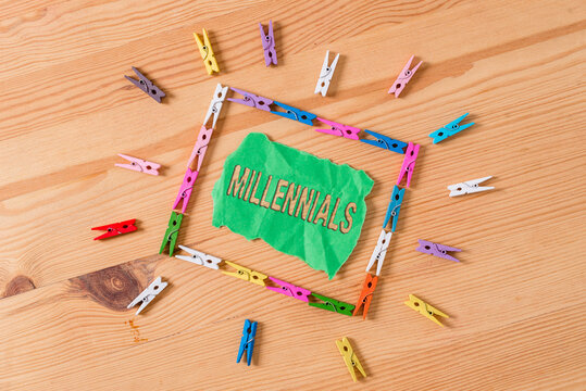 Conceptual hand writing showing Millennials. Concept meaning an individual reaching young adulthood in the early 21st century Colored crumpled papers wooden floor background clothespin
