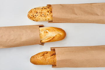 Wholegrain baguettes in paper bags. Fresh bread on white background. Gluten free pastry.