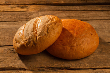 Two round loaves of homemade bread. Crusty bread on wooden background.