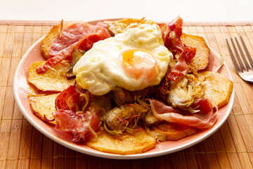 Huevos Rotos. Traditional spanish tapa with iberico ham, deep fried potatoes and fried egg.