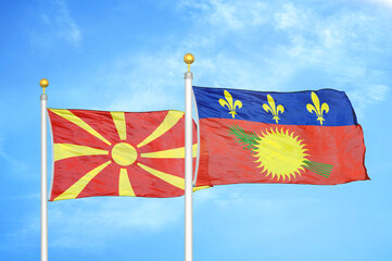 North Macedonia and Guadeloupe two flags on flagpoles and blue sky