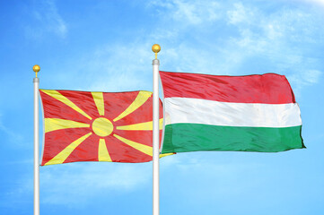 North Macedonia and Hungary two flags on flagpoles and blue sky