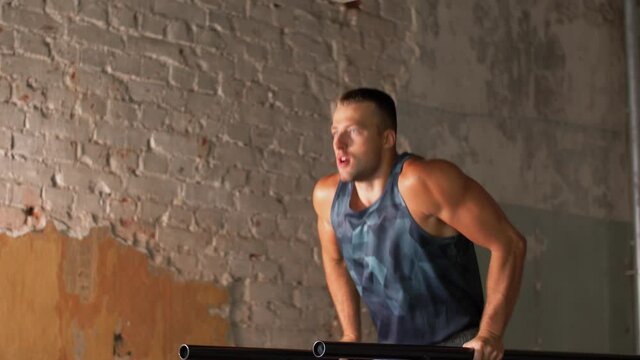 fitness, sport, bodybuilding and people concept - young man doing triceps dip exercise on parallel bars in gym
