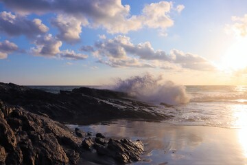 Impressive water splash fom wave hitting rocks at sunset