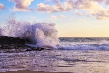 Huge splash from wave crashing against rocks at sunset