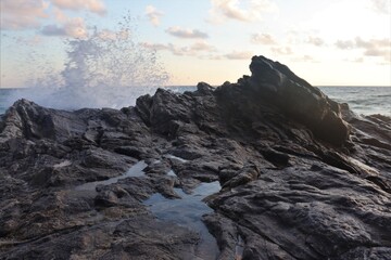 Big water splash on dark rocks into the evening sky 