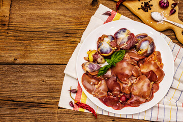 Fresh raw chicken offal: heart, liver, stomach with dry spices, sea salt, chili pepper on wooden table